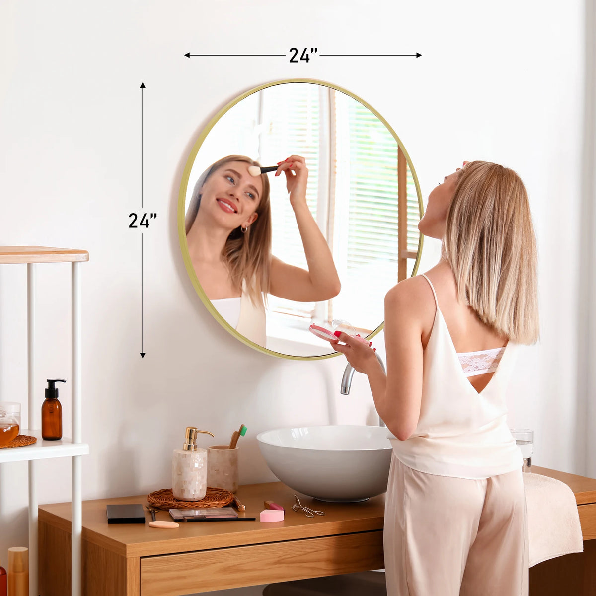 A woman is looking in a large round vanity mirror with a matte metal frame in a bright bathroom setting.