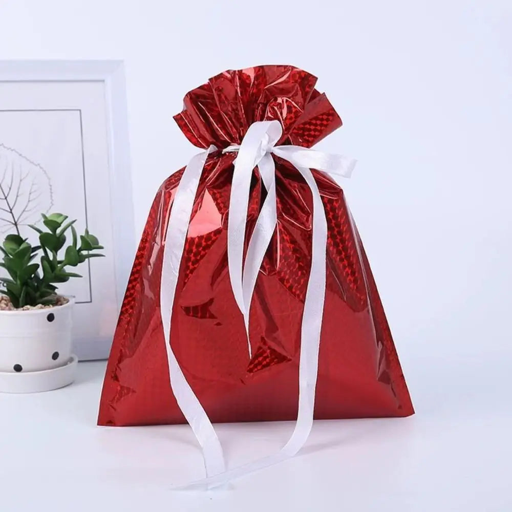 A red festive drawstring gift bag with a white ribbon, featuring Santa and snowman designs.