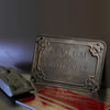 A vintage metal tin sign with the text ASYLUM FOR THE CRIMINALLY INSANE resting on a piece of paper.