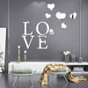 Silver acrylic heart wall stickers with a mirror finish displayed on a gray wall above a bench.