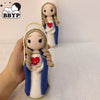 Handcrafted Virgin Mary crochet doll with brown hair and blue robe holding a red heart