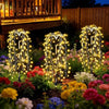 A display of solar garden lights with a starburst effect illuminating colorful flowers in a garden setting.