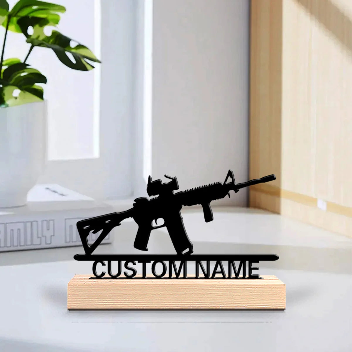 A black metal rifle statue with a wooden base engraved with custom name, displayed on a white desk.
