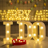 Three luminous LED alphabet night lights spelling I D O on a white surface with a red coaster.