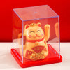 A solar-powered waving lucky cat figurine in a clear box on a red base.