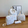 A set of white backpacks and accessories featuring a red bow print on a wooden surface.