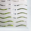 Close-up of frosted glass window privacy film featuring wavy, silver and green lines.