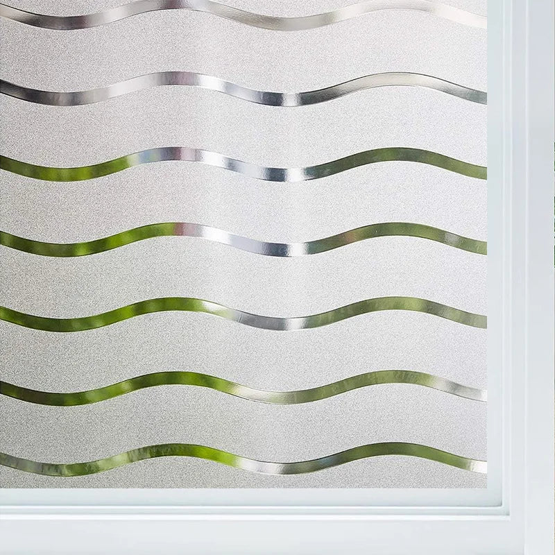 Close-up of frosted glass window privacy film featuring wavy, silver and green lines.