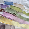 A collection of decorative fishtail yarn ribbons in various pastel shades, including blue, purple, green, and yellow.