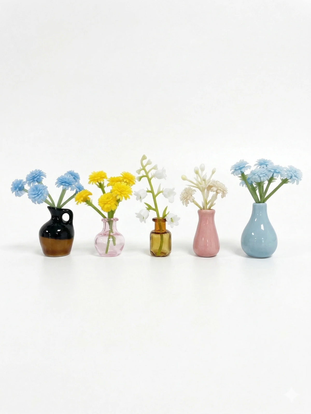 A collection of mini ceramic vases holding various colorful flowers like blue and yellow blossoms.