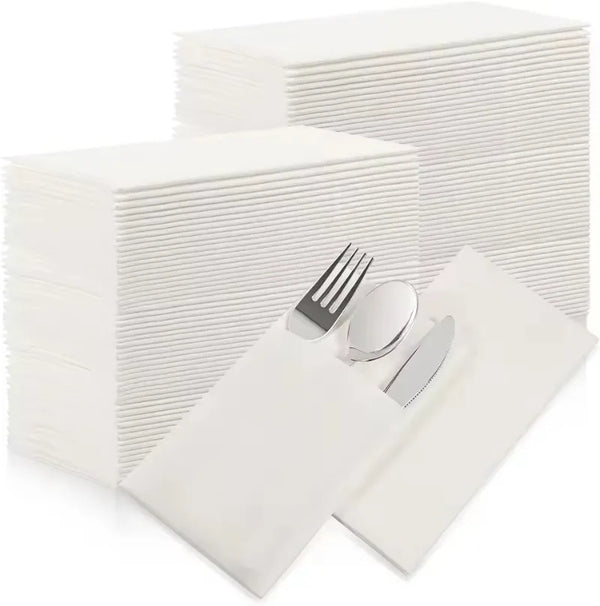 A stack of white disposable paper napkins is shown next to a neatly folded white napkin and silverware.