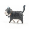 A small, dark gray and white cartoon cat figurine with a blue eye and a brown collar.