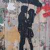 Graffiti art featuring a silhouette of two figures under a black umbrella on a textured wall.