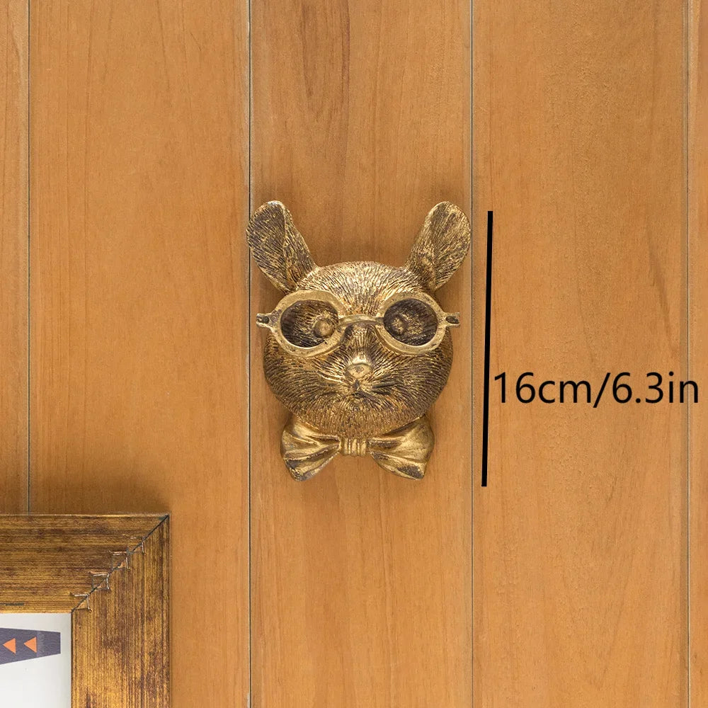 A brass deer head storage hook wall decor with large eyes and ears is displayed against a wooden background.