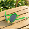 Green alien sunglasses resting on a wooden surface outdoors