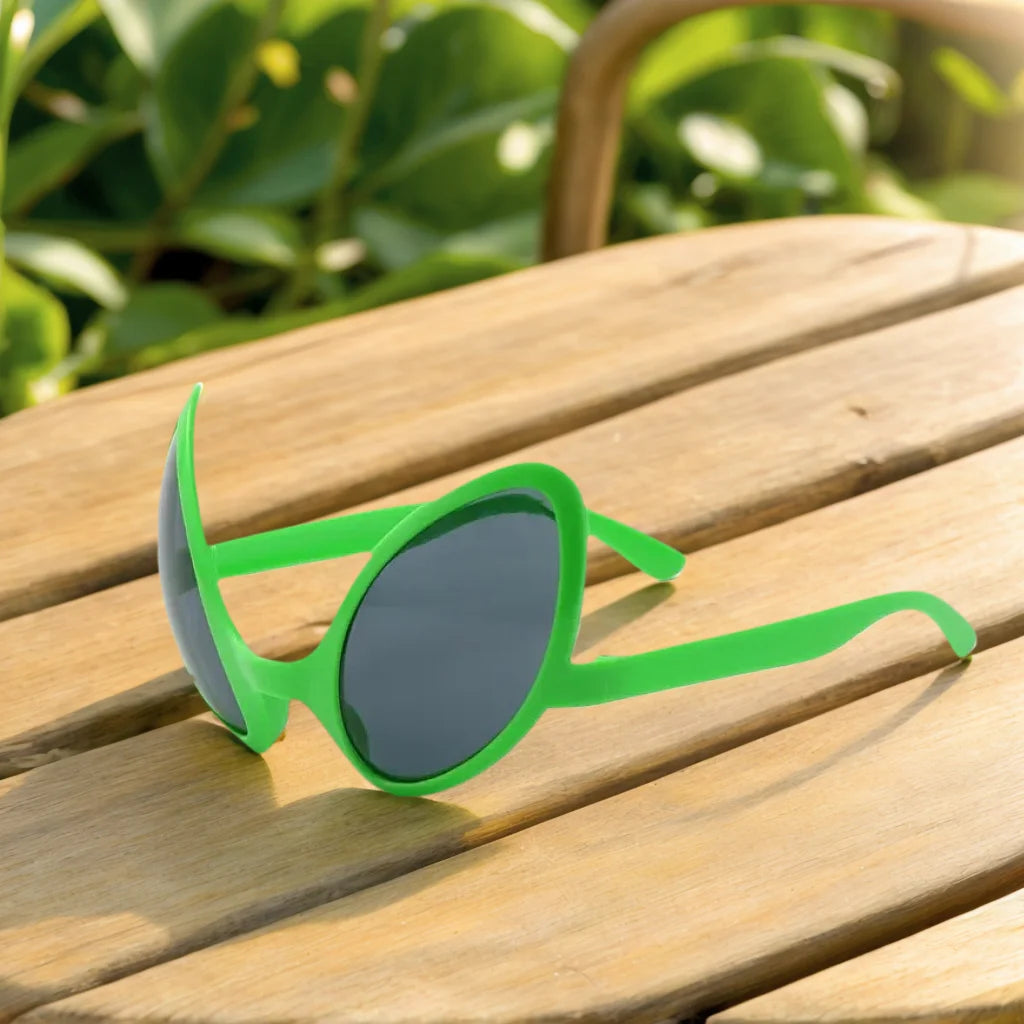 Green alien sunglasses resting on a wooden surface outdoors