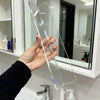 A hand holds a clear acrylic shelf divider used for cabinet and mirror storage.