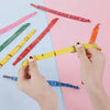 Hands holding and arranging colorful rocket balloon strips on a pink background.