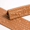 A close-up of a copper-colored self-adhesive PVC corner trim with a 3D textured edge.