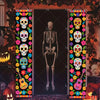 A vertical banner featuring colorful Mexican skull and floral motifs displayed in a doorway setting.