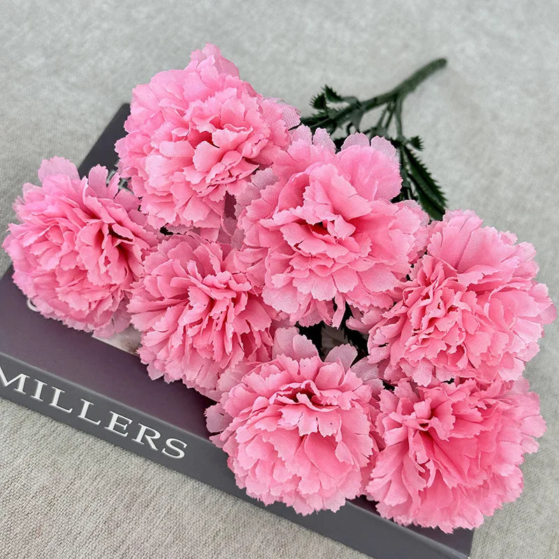 A bouquet of pink silk artificial chrysanthemum flowers displayed on a dark box.