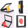 A black floating shadow box display frame showing yellow and red oval gift boxes.
