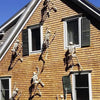 A brown wooden house exterior with shadows of skeleton decorations cast on the siding.
