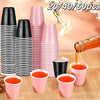A collection of pink and black mini plastic shot cups stacked and displayed on a wooden surface.