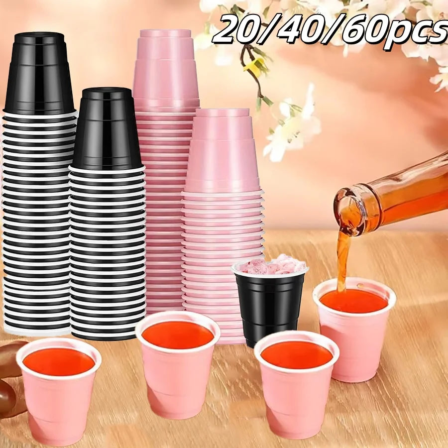 A collection of pink and black mini plastic shot cups stacked and displayed on a wooden surface.