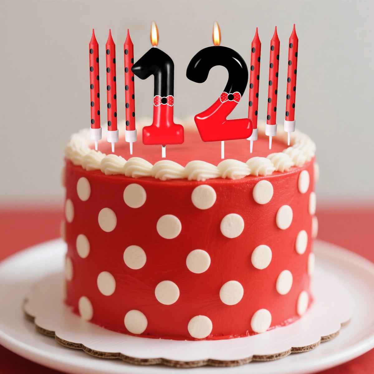 A red birthday cake decorated with red and black polka dots, topped with number candles 1 and 2.