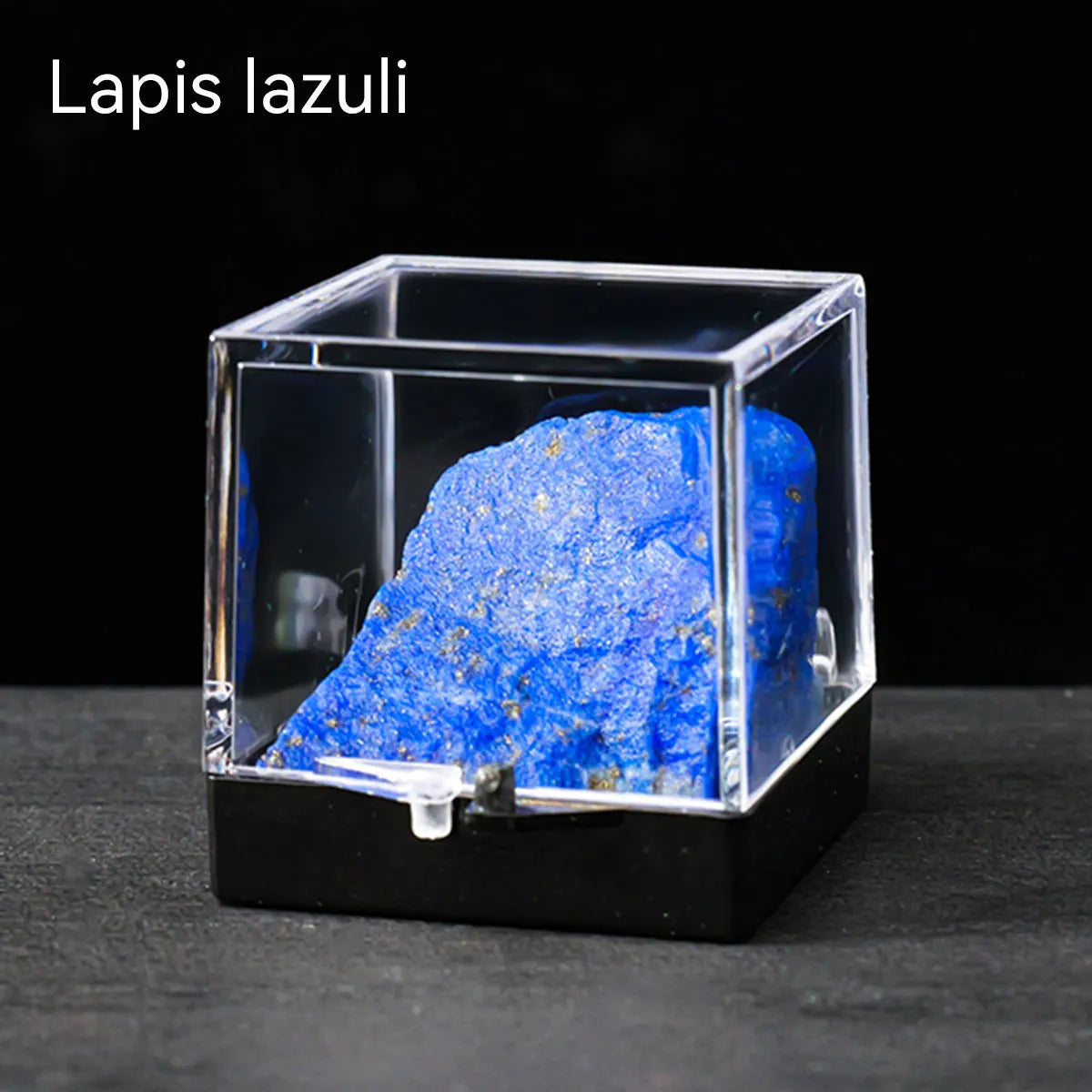 A rough blue lapis lazuli crystal specimen displayed inside a clear glass box.