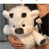 A white West Highland Calf plush toy is being held by a person.