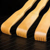 Three light wood bamboo back scratchers or roller massagers laid diagonally on a dark surface.