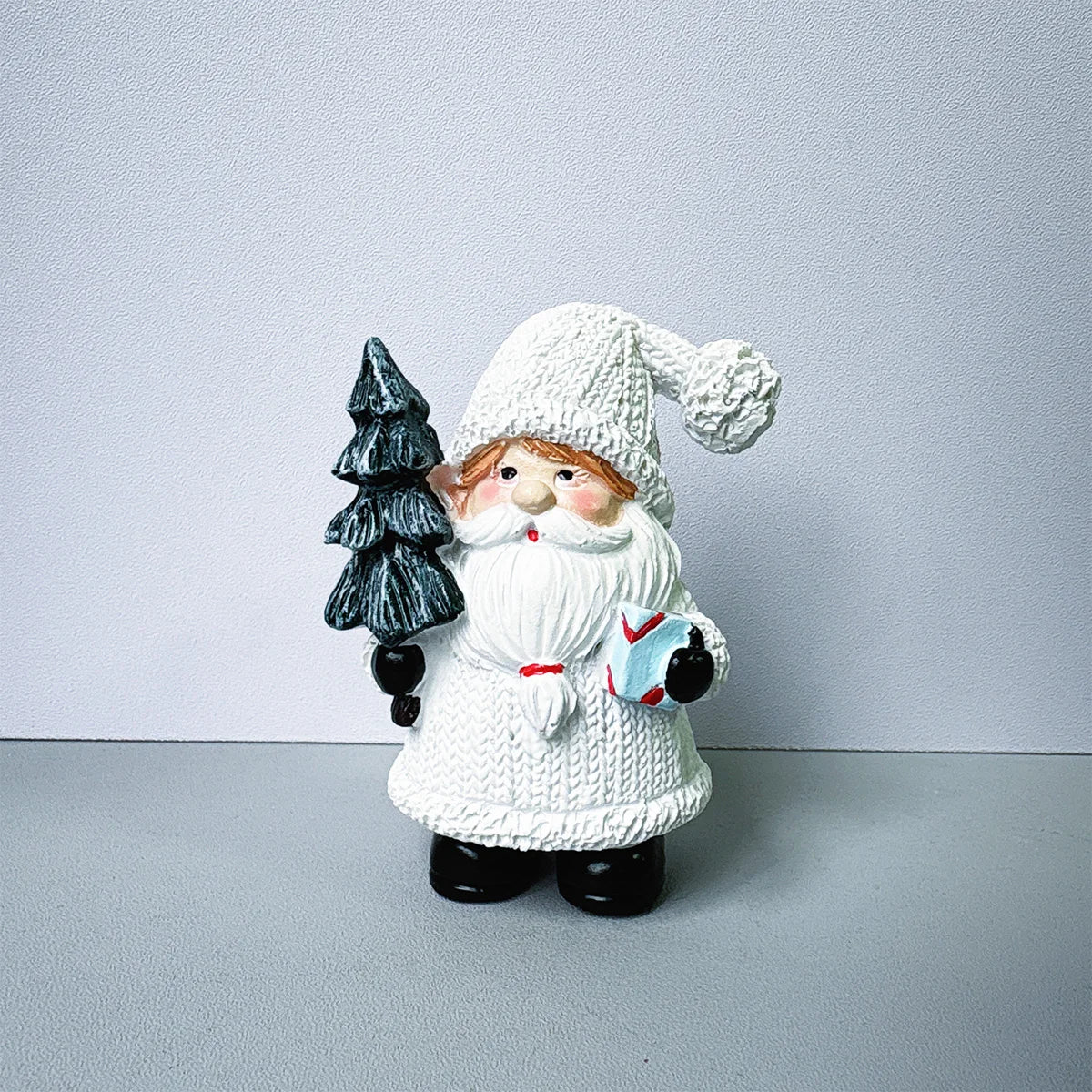 Adorno de Papá Noel de resina tejido blanco con barba y sombrero contra un fondo gris claro.