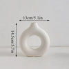 A white modern ceramic circular vase with a smooth, organic shape.
