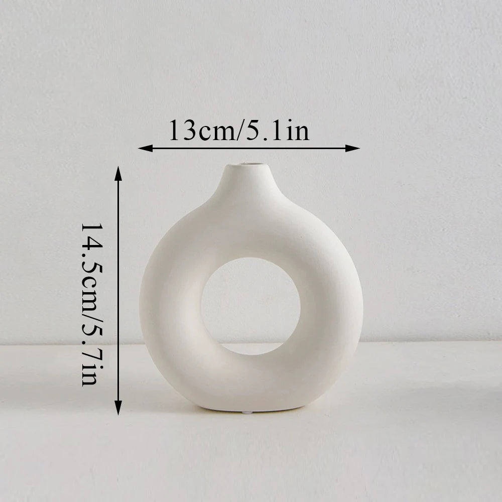 A white modern ceramic circular vase with a smooth, organic shape.