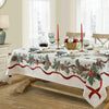 A Christmas poinsettia rectangle tablecloth set for a dining table with candles and tableware.
