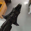 A dark, sculpted figurine of a woman with flowing hair and drapery, resembling a gothic reaper.
