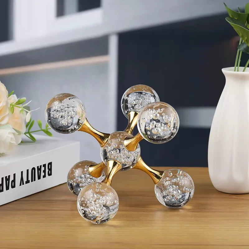 A gold-toned molecular sculpture desk decor featuring spherical glass orbs with glitter inside.