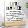 An acrylic desk sign featuring positive reminders like You are enough and Be kinder to yourself.