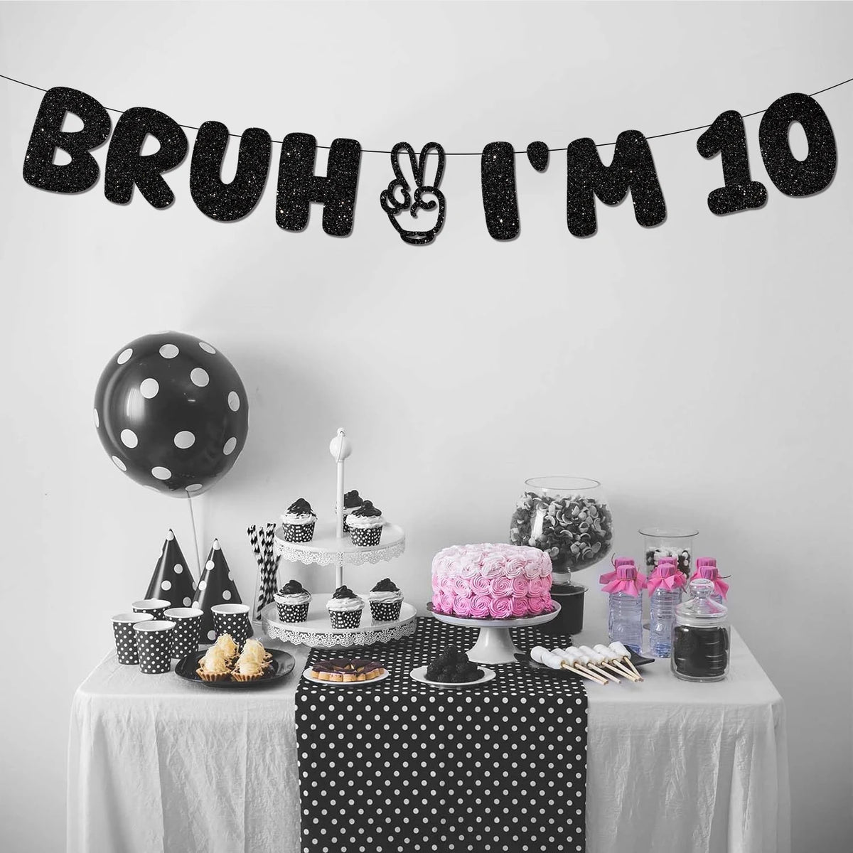 A black glitter banner spelling out Bruh I'm 10 for a birthday party decoration setup.