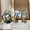 A silver robotic hand and a white game controller are displayed on a shelf with a mirror.