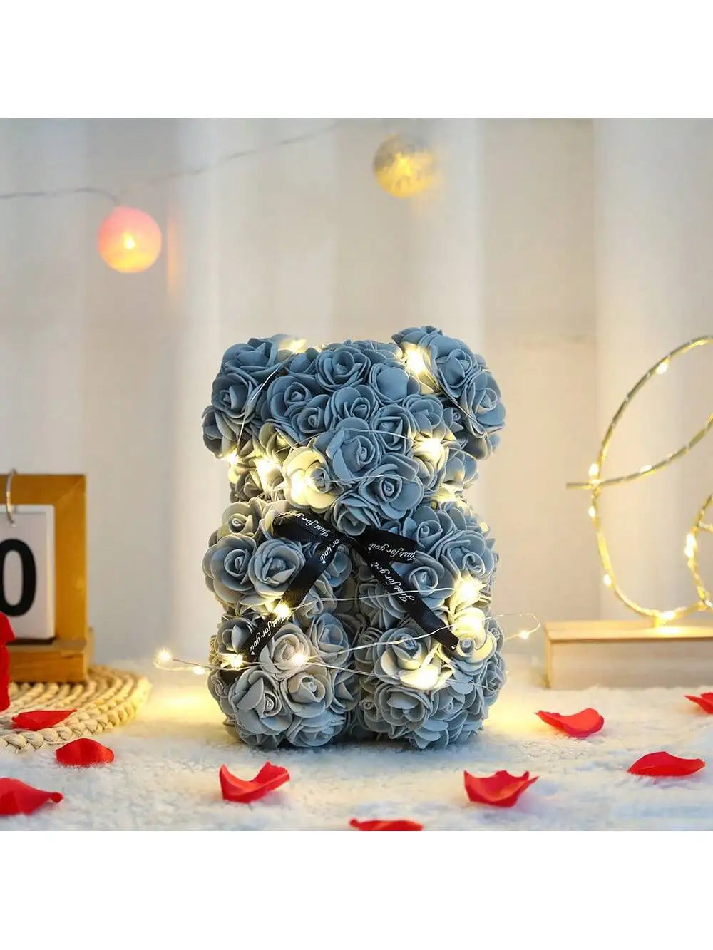 Flauschiger künstlicher Rosen-Teddybär mit warmen Lichterketten auf weißem Untergrund.