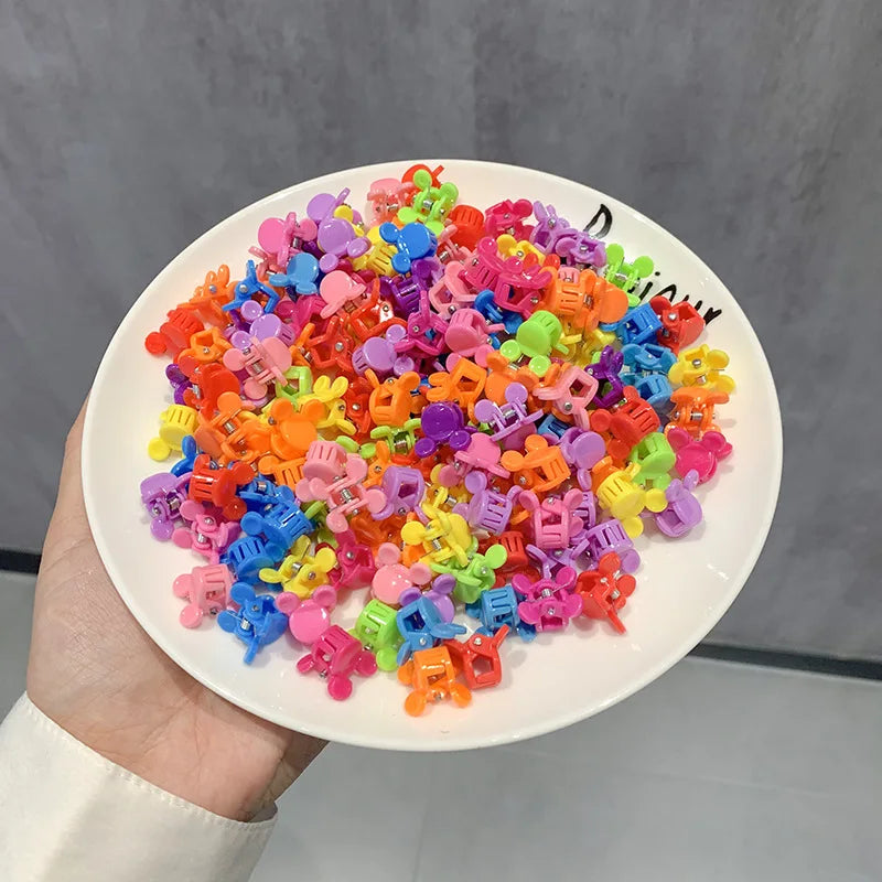 A pile of colorful flower and star hair claw clips for kids on a white plate.