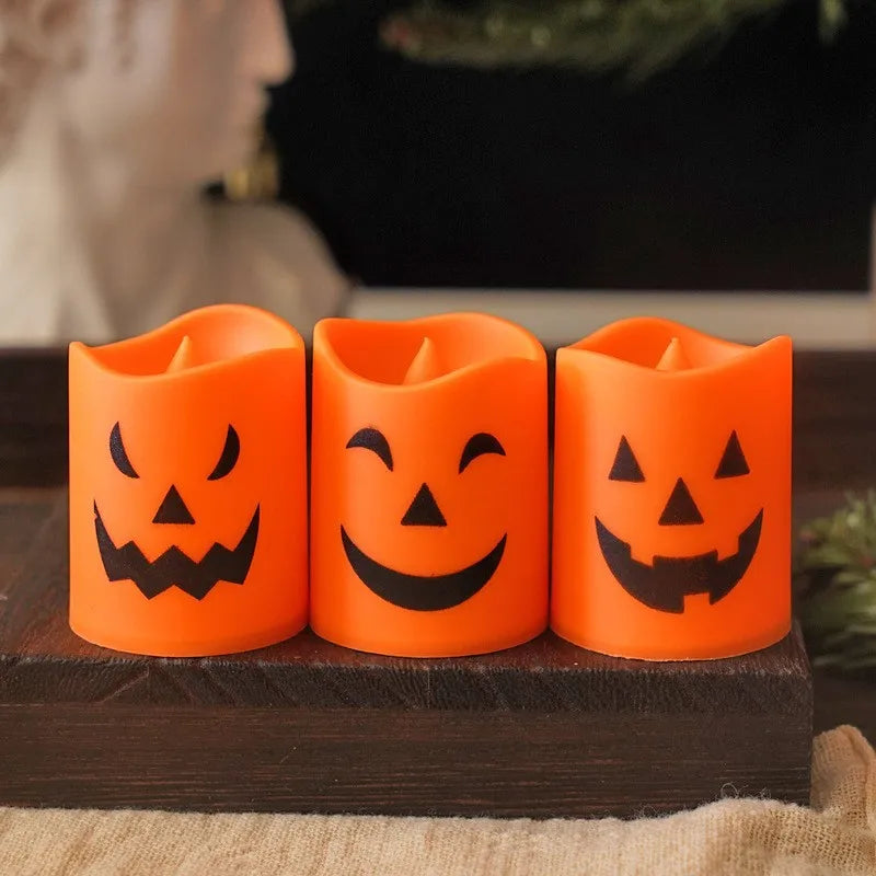 Three orange flameless LED candles shaped like carved pumpkins sitting on a dark wooden surface.