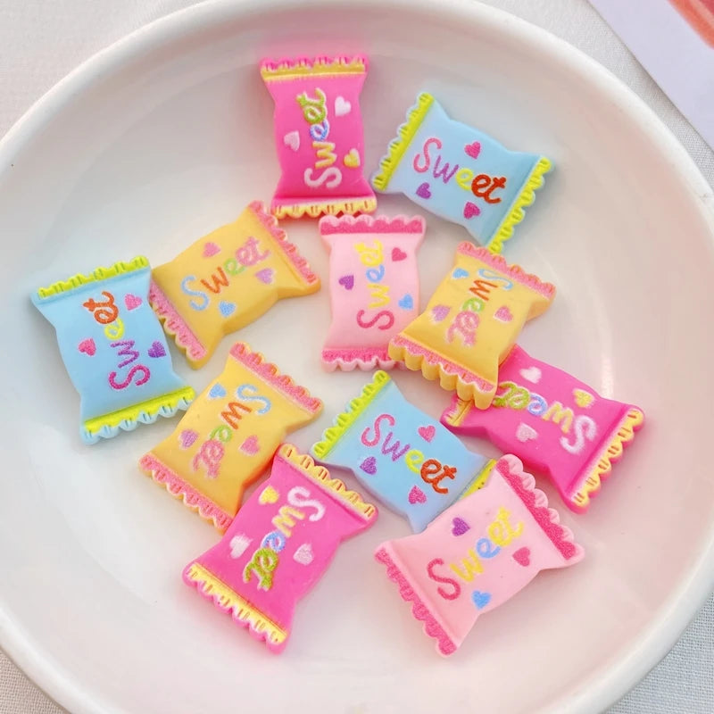 A collection of twenty-piece pink and yellow resin candy charms with sweet lettering arranged on a white plate.