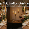 A set of three vintage European style metal candle holders with lit candles on a wooden table setting.