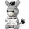 A handmade crochet donkey ornament with black hair and a humorous message on its body.