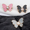 A set of three pearl butterfly buttons in pink, black, and silver are shown against a dark denim background.