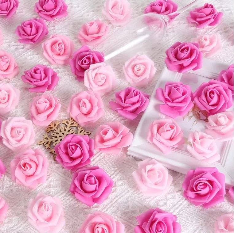A collection of artificial foam roses in various shades of pink and magenta scattered on a white surface.